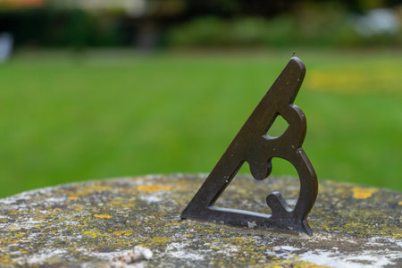 a close up of a sun dial on a stone stand in a garden