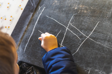 A child's hand drawing on a blackboard with chalkの写真素材