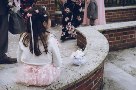 a flower girl sitting on a wall outside a churchの写真素材