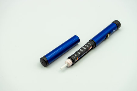 An insulin injection pen used by diabetics with insulin inside next to its lid isolated on a white backgroundの写真素材