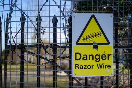 A sign stating danger razor wire in a fenceの写真素材