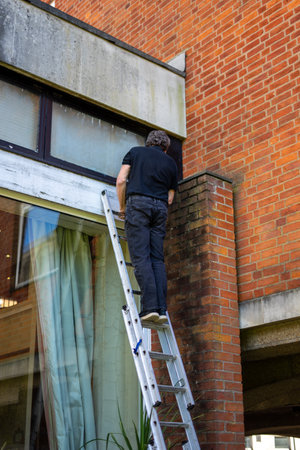 A Builder climbing a ladder to carry out repair workの写真素材
