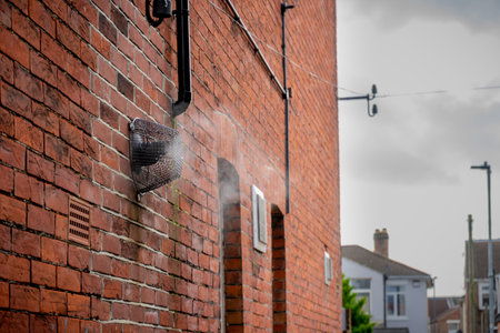 a boiler steam vent on the side of a brick house bellowing steam on a cold winter dayの写真素材