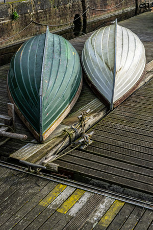 Two old wooden boats upturned on a wooden jettyの写真素材
