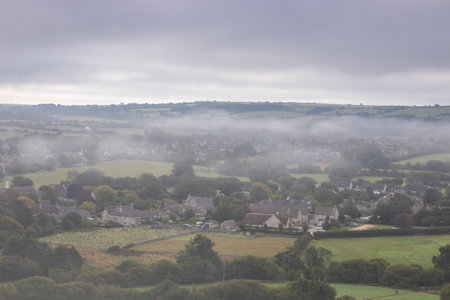 A typical old English village in a valley with mist creeping in over the hillsの写真素材