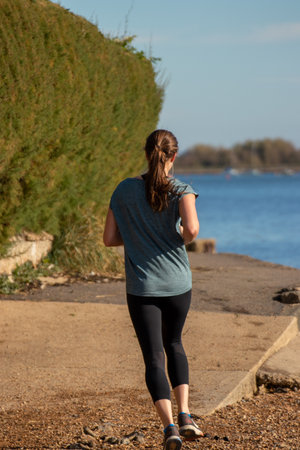 A young woman jogging alone along the shore sideの写真素材