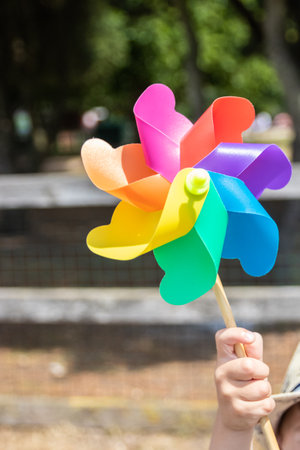 A hand holding up a childs milti coloured rainbow windmillの写真素材