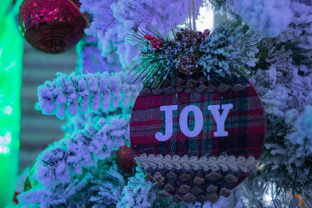 A christmas tartan bauble decoration with the word joy on it hanging on a christmas treeの写真素材