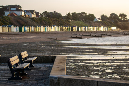 Empty benches at the seaside with beach huts in the backgroundの写真素材