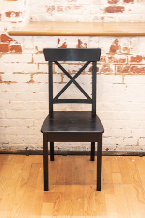 a single wooden chair up against a brick wallの写真素材