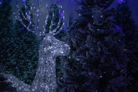 A deer stag christmas decoration next to a christmas tree and christmas lightsの写真素材