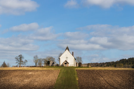 an old church on a hill surrounded by ploughed fieldsの写真素材