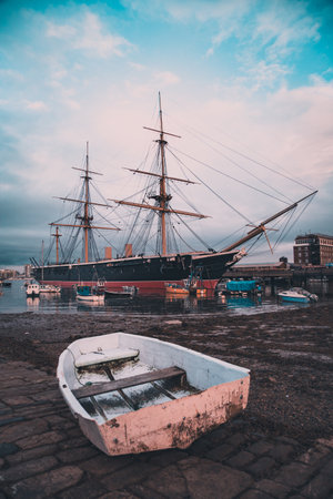 HMS Warrior moored in Portsmouth with an old fishing boat in the foregroundの写真素材
