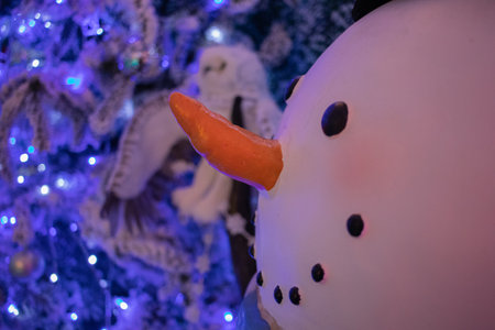 a snowman christmas decoration in front of a christmas treeの写真素材