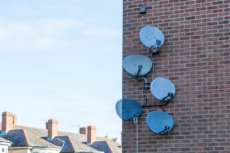 A Group of satellite dishes on the side of a brick buildingの写真素材