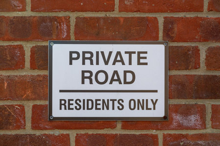 A sign on a brick wall stating Private road residents onlyの写真素材
