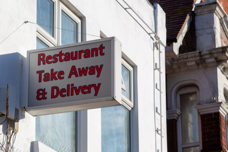 A sign outside a takeaway restaurant stating restaurant takeaway and deliveryの写真素材