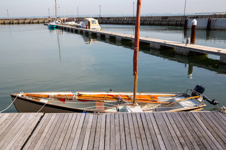 a wooden sailing boat moored at an old wooden jetty