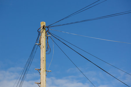 Telephone lines on a wooden pole or telegraph pole in a street heading off to different homesの写真素材