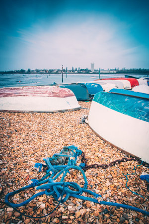 upturned wooden fishing boats and ropes on a sea shoreの写真素材