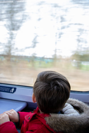a small boy looking at the window on a moving trainの写真素材