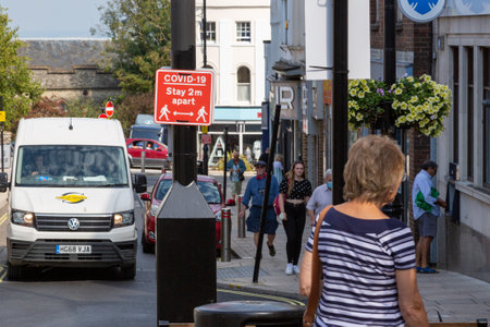 09/15/2020 Ryde, Isle of Wight, UK People walking past a sign in the street that states covid-19...