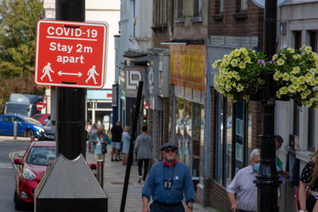 09/15/2020 Ryde, Isle of Wight, UK People walking past a sign in the street that states covid-19 stay two meters apartのeditorial素材
