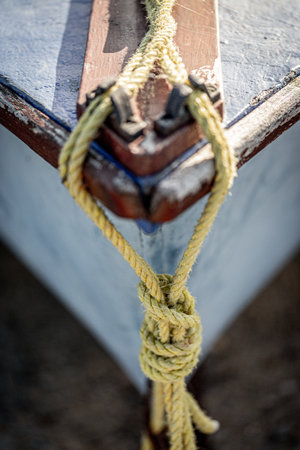 A close up of boat ropes tied up around the cleat on the bow of a wooden boat using selective focusの写真素材