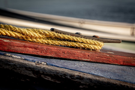 A close up of boat ropes tied up around the cleat of a wooden boat using selective focusの写真素材