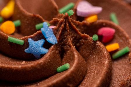 A close up of the icing and sprinkles on a chocolate cupcake using selective focusの写真素材