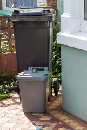 A Black wheelie bin with a food recycling bin outside a home ready for collectionの写真素材
