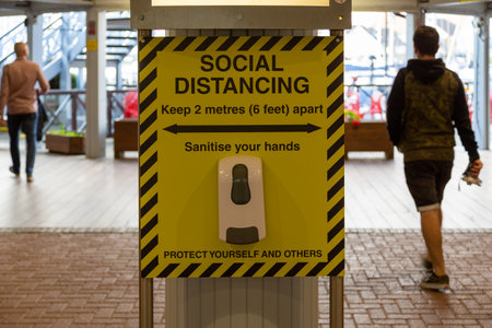 Alcohol hand gel under a social distancing sign for the use of the public when entering a shopping centreの写真素材