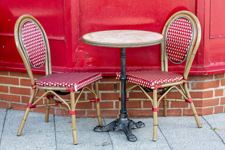 Two empty dining chairs either side of a table outside a restaurant or cafeの写真素材