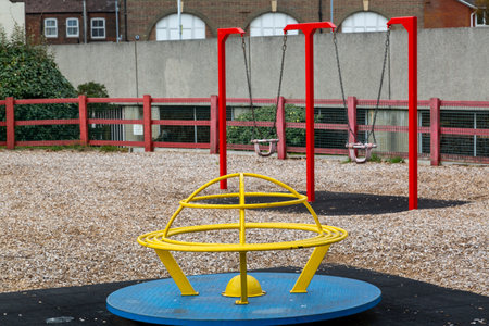 A empty children's play area or park showing a roundabout and swingsの写真素材