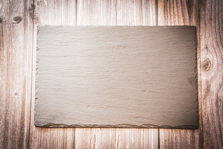 A slate plate on a wooden background with copy spaceの写真素材