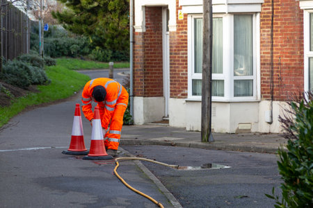 A maintenance worker in high visibility clothing laying out cones in a streetの写真素材