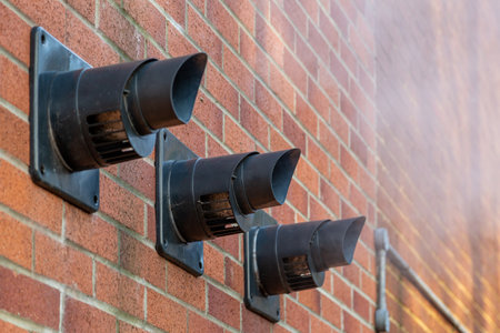 Three central heating boiler flues releasing steam on the exterior of a brick houseの写真素材
