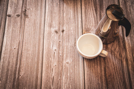 A silver coffee pot and white coffee cup on a rustic wooden background with copy spaceの写真素材