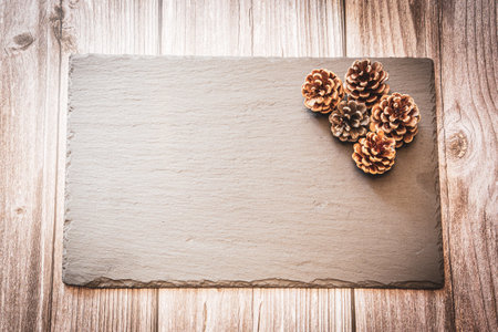 Pine cones on a slate resting on a wooden background with copy space, an autumn backgroundの写真素材