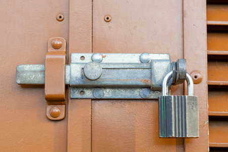 A close up of a metal slide lock and a padlock on the exterior of a doorの写真素材