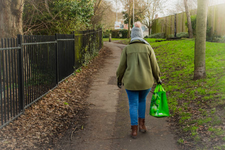 A woman walking alone in the street carrying a shopping bagの写真素材