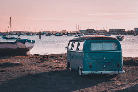 A vintage camper van parked near the sea at sunsetのeditorial素材