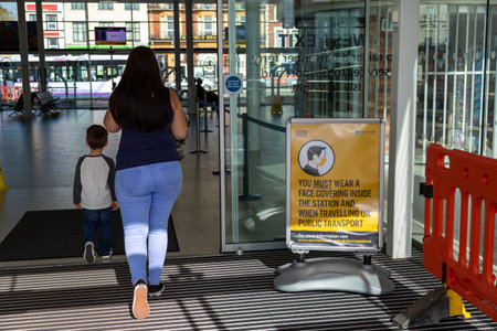 09/08/2020 Portsmouth, Hampshire, UK A mother and child walking past a sign showing that face masks or face coverings must be wornのeditorial素材