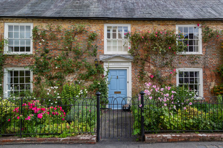 The exterior of an english cottage with flowers blooming in the front garden and sash windows, A typical english countryside cottageのeditorial素材
