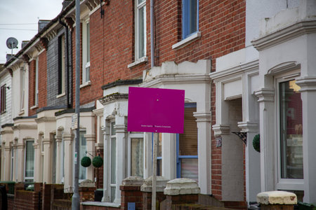 An estate agents sign outside a row of British terraced houses