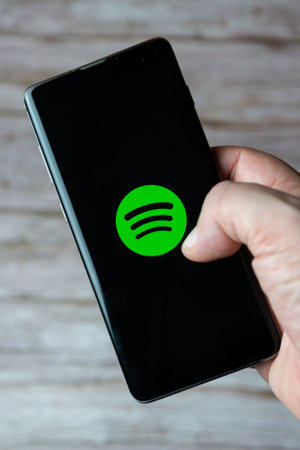 01-30-2021 Portsmouth, Hampshire, UK A hand holding a mobile phone or cell phone with the Spotify music app open on screenのeditorial素材