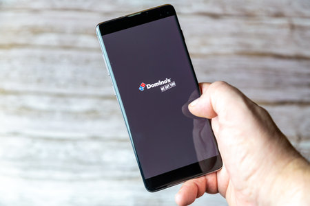 01-30-2021 Portsmouth, Hampshire, UK A hand holding a mobile phone or cell phone with the Domino's Pizza delivery app open on screenのeditorial素材