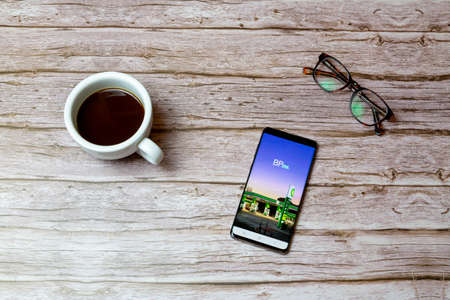 02-04-2021 Portsmouth, Hampshire, UK A Mobile phone or cell phone laid on a table or desk with the BP points app open and a coffee next to itのeditorial素材