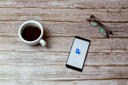 02-04-2021 Portsmouth, Hampshire, UK A Mobile phone or cell phone laid on a table or desk with the Google translate app open and a coffee next to itのeditorial素材