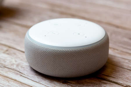 02-04-2021 Portsmouth, Hampshire, UK An Amazon Echo dot or amazon Alexa device isolated on a wooden table or deskのeditorial素材